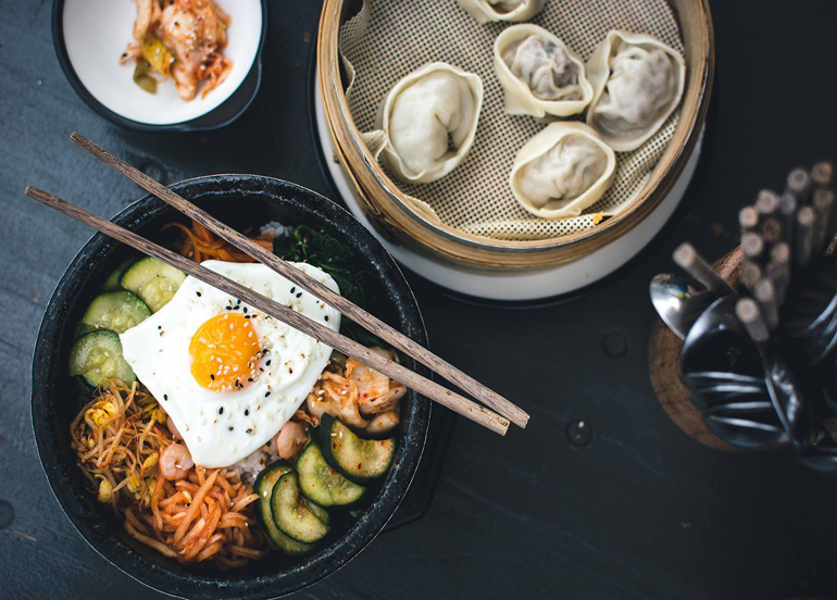 Bibimbap and Korean dumplings with chopsticks and utensils