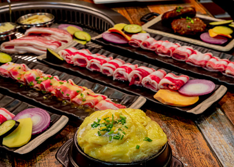 Vibrantly-colored samgyupsal lined up, egg with spring onion on top