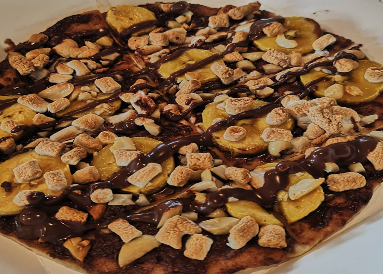 Hazelnut Banana Crunch Dessert Pizza drizzled with hazelnut sauce, bananas, marshmallows, and nuts