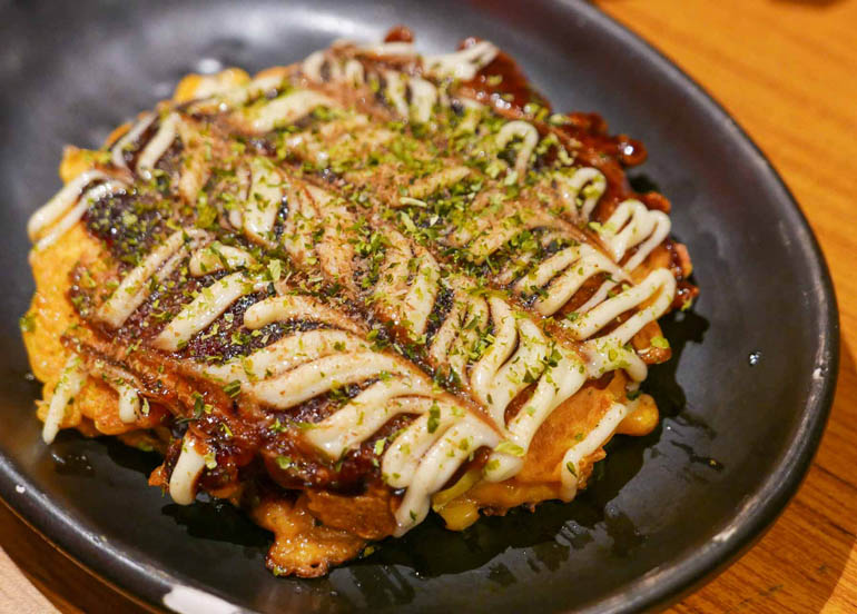 Okonomiyaki from Dohtonbori topped with Japanese mayo, nori flakes, and sauce.