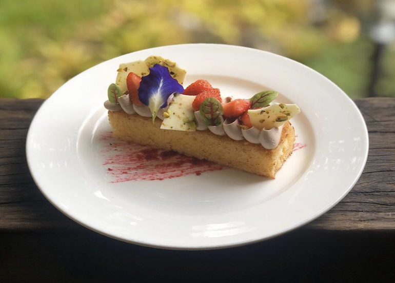 Lemuria dessert tart topped with cream, white chocolate, edible flowers, and fruit